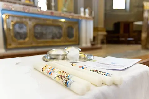 Candeline bianche decorate e oggetti liturgici sull'altare prima del battesimo in chiesa – servizio fotografico a Milano