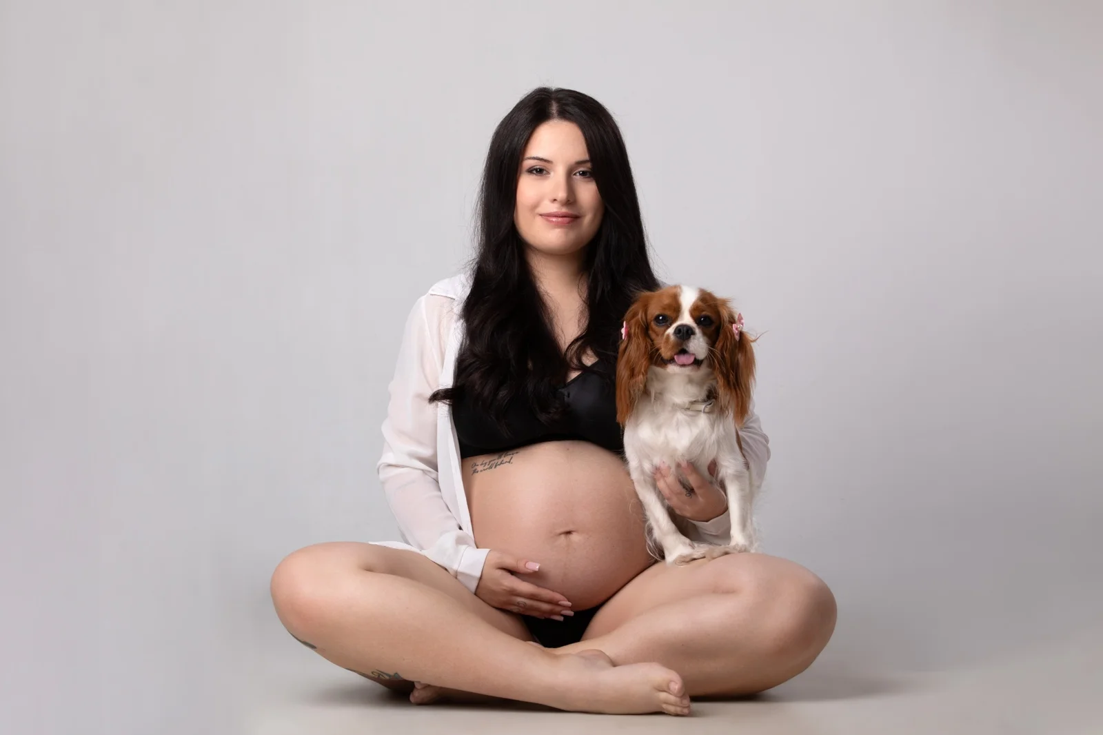 Donna incinta posa con la sua cagnolina durante servizio fotografico gravidanza in studio