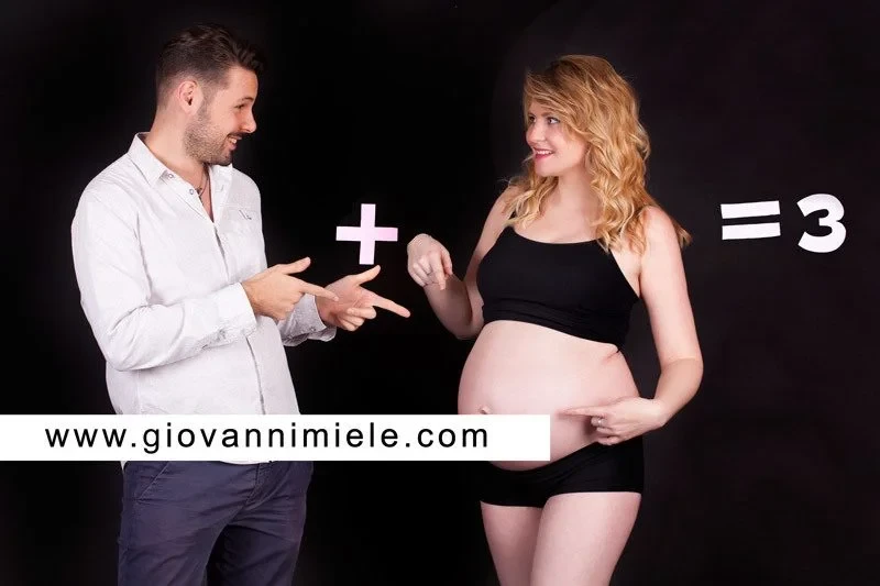 Uomo con ecografia in mano e donna incinta sullo sfondo in studio fotografico