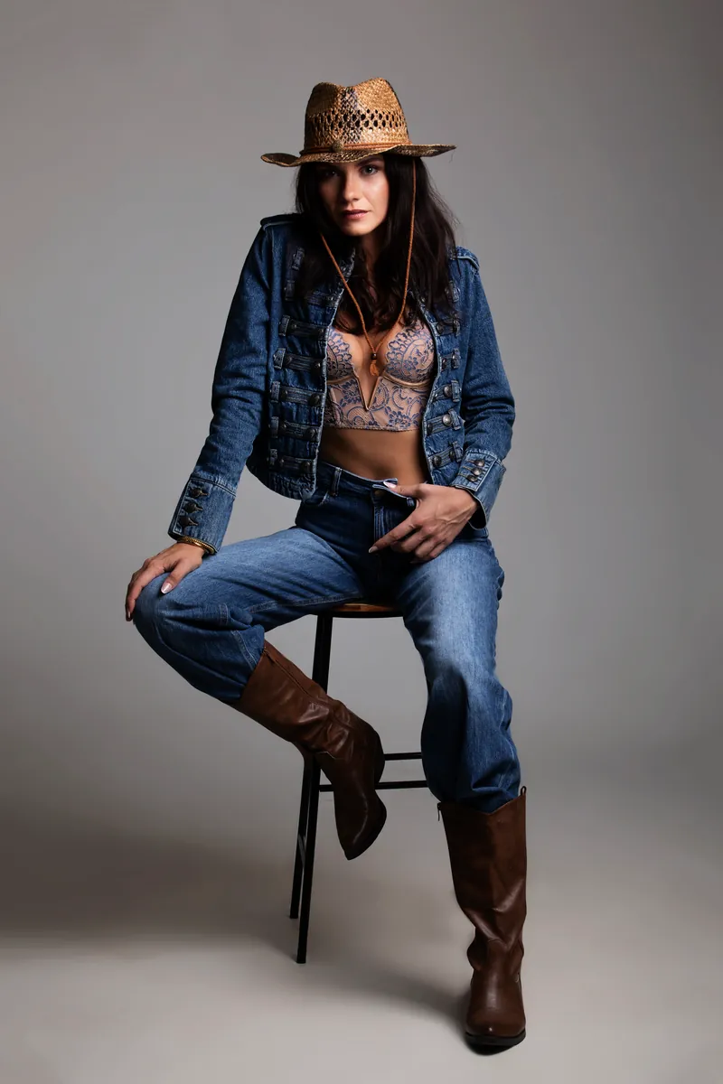 Donna in completo denim e cappello di paglia, seduta su uno sgabello