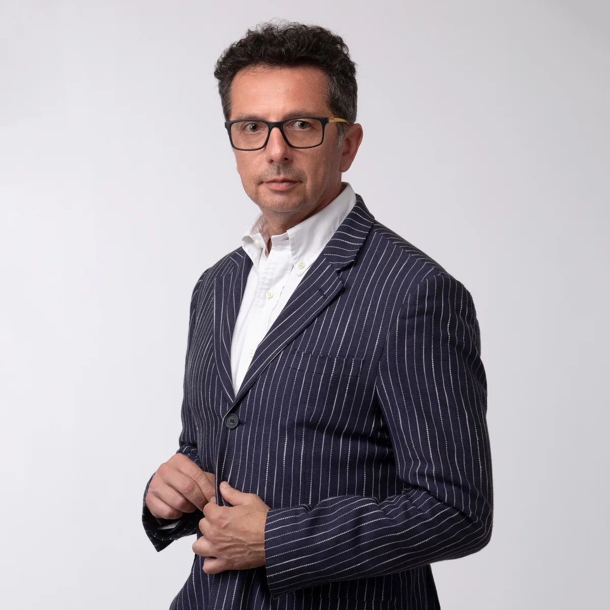Headshot LinkedIn di un uomo con occhiali in abito gessato blu, fotografo a Milano