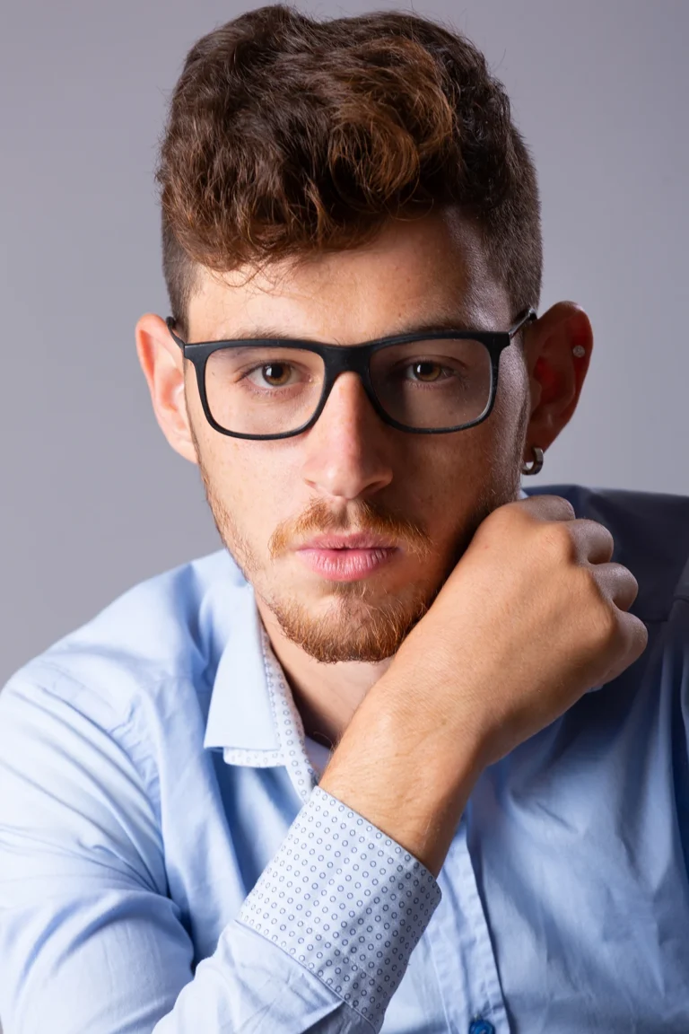 Primo piano di attore con occhiali e camicia azzurra